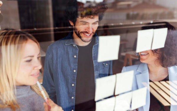 Business group of people creating a plan sticking sticky labels on a window in a stylish and bright coworking space
